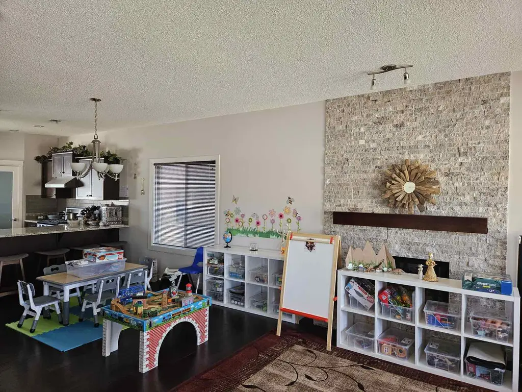 Bright main play area at Little Steps with Smita - kids' table, art easel, organized toy shelving and flower wall decals